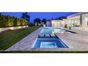 Gorgeous backyard with pool, spa, and travertine decking illuminated at night, ideal for entertaining at 6614 E North Ln, Paradise Valley, AZ 85253
