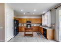 Well-lit kitchen with wooden cabinets, black appliances, granite countertops and a movable island at 7624 E Plata Ave, Mesa, AZ 85212