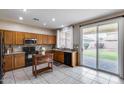 Eat-in kitchen with tiled floors, wooden cabinets and black appliances, leading to the backyard at 7624 E Plata Ave, Mesa, AZ 85212