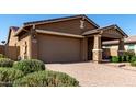 Front exterior featuring a two-car garage, covered porch with stone accents, and well-maintained landscaping at 10307 E Tiburon Ave, Mesa, AZ 85212