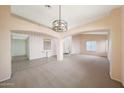 Open-concept living room featuring plush carpeting, neutral walls, and decorative hanging light fixture at 10613 E Nacoma Dr, Sun Lakes, AZ 85248