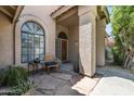 Inviting covered front porch with stylish seating, stone tile, arched window, and decorative front door at 1243 W Sherri Dr, Gilbert, AZ 85233