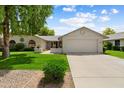 Single-story home featuring a two-car garage, well-maintained lawn, and desert landscaping under a blue sky at 13023 W Tangelo Dr, Sun City West, AZ 85375