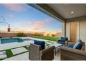 Serene outdoor patio area with comfortable seating overlooking a private pool and a picturesque backyard with views at 16566 W Saguaro Park Ln, Surprise, AZ 85387
