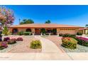 Charming single-story home featuring a red tile roof, arched windows, desert landscaping, and a concrete walkway under a blue sky at 2232 E Inglewood St, Mesa, AZ 85213