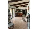 Open-concept living space with beamed ceilings, tile flooring, and barstool seating at 2232 E Inglewood St, Mesa, AZ 85213