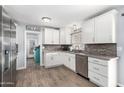 Bright kitchen featuring white cabinets, stainless steel appliances, mosaic backsplash, and wood-look floors at 25615 S Lemon Ave, Queen Creek, AZ 85142