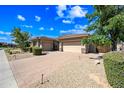 Charming home with manicured desert landscaping and a brick driveway leading to an attached three-car garage at 2565 N 141St Ln, Goodyear, AZ 85395