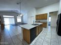 Open kitchen features tile flooring, a kitchen island with a sink, and natural wood cabinetry at 8006 W Gibson Ln, Phoenix, AZ 85043