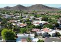 An aerial view of a residential neighborhood with white houses, red tile roofs, and desert landscaping near mountains at 9430 S 47Th Pl, Phoenix, AZ 85044