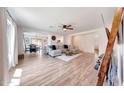 Bright and airy living room featuring wood-like floors, a ceiling fan, and seamless flow to other rooms at 13443 W Post Dr, Surprise, AZ 85374