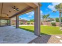 Covered back patio that overlooks a beautiful backyard featuring artificial turf, a pool with waterfall, and lush plants at 1526 E Glacier Pl, Chandler, AZ 85249