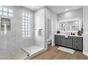 Bright bathroom with glass enclosed shower with stone floor, framed mirror, and gray vanity at 1526 E Glacier Pl, Chandler, AZ 85249