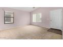 Light-filled living room with neutral carpet and multiple windows at 15835 W Woodlands Ave, Goodyear, AZ 85338