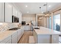 Modern kitchen features an island, white cabinets, stainless steel appliances, and decorative backsplash at 1895 N 141St Ave, Goodyear, AZ 85395