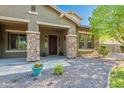 Close-up of the house with a covered porch and stone pillars, enhanced by desert landscaping at 2735 E Flower Ct, Gilbert, AZ 85298