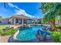 Resort-style pool with rock waterfall features, lounge chairs, and lush landscaping in the private backyard at 3736 E Cotton Ct, Gilbert, AZ 85234