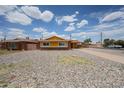 A single-story brick home with yellow trim featuring a low-maintenance rock front yard at 4102 W Maryland Ave, Phoenix, AZ 85019