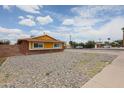 A single-story brick home with yellow trim and low-maintenance rock front yard at 4102 W Maryland Ave, Phoenix, AZ 85019