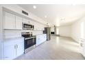 Bright and modern kitchen featuring stainless steel appliances, sleek white cabinetry, and tile floors at 4528 W Butler Dr, Glendale, AZ 85302