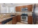 Well-lit kitchen featuring stainless steel appliances, granite countertops, and wood cabinets at 5757 S 21St Ter, Phoenix, AZ 85040
