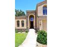 Beautiful home entrance with stone accents, arched windows, and a lush, green lawn at 7272 W Crystal Rd, Glendale, AZ 85308