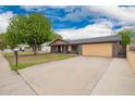 Single-story house featuring a spacious driveway and large garage at 7755 W Cora Ln, Phoenix, AZ 85033