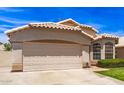 Charming single-story home with a tile roof, manicured lawn, and a two-car garage on a sunny day at 7930 W Wescott Dr, Glendale, AZ 85308
