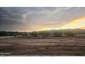 Large lot at sunset with a white fence bordering the property, presenting amazing potential at 8678 S John Jacob Astor Ave, Casa Grande, AZ 85193