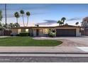Charming one-story home with fresh landscaping, illuminated windows, and a brick-paved driveway at dusk at 1535 E Kenwood St, Mesa, AZ 85203