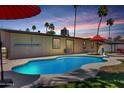 Sparkling pool surrounded by a concrete patio, lush greenery, and palm trees under a colorful sunset sky at 1535 E Kenwood St, Mesa, AZ 85203