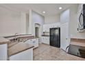 An open concept kitchen showcasing white cabinets, black appliances, granite counters, and tile flooring at 16874 W Tonbridge St, Surprise, AZ 85374