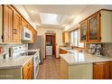 Bright kitchen featuring wood cabinets, quartz counters, stainless appliances, and a skylight for natural lighting at 1708 E Westchester Dr, Tempe, AZ 85283