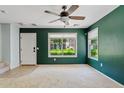 Bright living room with white carpet, ceiling fan and sunlit windows overlooking the landscaped front yard at 3623 E Horace Dr, Gilbert, AZ 85296