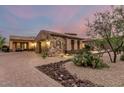 Charming home with stone accents, warm lighting, and a paved driveway surrounded by desert landscaping at 37301 N 99Th St, Scottsdale, AZ 85262