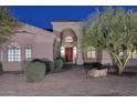 Close-up showcasing the home's entrance with arched portico, solid wood double doors, and stone pathway at 39241 N Boulder View Dr, Scottsdale, AZ 85262