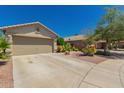 Well maintained single story house with tan exterior, two-car garage and desert landscaping at 6031 N Milano Ct, Litchfield Park, AZ 85340