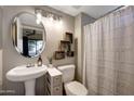 Bathroom featuring pedestal sink, round mirror and decorative floating shelves at 7857 N 21St Ave, Phoenix, AZ 85021