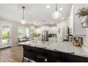 Bright, white kitchen with stainless steel appliances, a large island with seating, and modern pendant lighting at 11526 E Shepperd Ave, Mesa, AZ 85212