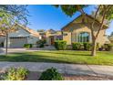 Well-manicured single-story home boasts a lush lawn and a convenient two-car garage under a bright blue sky at 2045 E San Carlos Pl, Chandler, AZ 85249