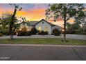 Beautiful house exterior showcasing mature trees, a green lawn, fresh landscaping, and well lit facade at dusk at 20644 E Sunrise Ct, Queen Creek, AZ 85142