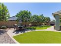 This backyard features a manicured lawn, mature trees, and an outdoor dining table with seating for six at 23179 S 225Th Pl, Queen Creek, AZ 85142