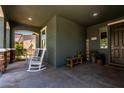 Welcoming covered porch with rocking chairs and a decorative welcome sign at 23179 S 225Th Pl, Queen Creek, AZ 85142