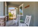 Inviting front porch featuring white rocking chairs, neutral color scheme, and stone accents at 23179 S 225Th Pl, Queen Creek, AZ 85142