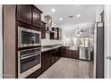 Modern kitchen boasts stainless steel appliances, dark wood cabinets, granite countertops, and stylish tile flooring at 2368 E Bellerive Dr, Gilbert, AZ 85298