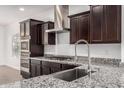 Close-up of a modern kitchen featuring stainless steel appliances, granite countertops, and dark wood cabinets at 2368 E Bellerive Dr, Gilbert, AZ 85298