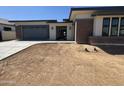Charming single-story home featuring a brick accent wall, gray garage door, and desert landscaping at 24000 S 218Th Pl, Queen Creek, AZ 85142