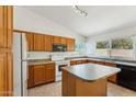 Functional kitchen with wood cabinetry, essential appliances, and a central island for meal preparation and casual dining at 4202 E Brookwood Ct, Phoenix, AZ 85048
