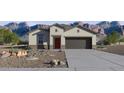 Charming single-story home featuring desert landscaping, a two-car garage, and a stucco facade against a mountain backdrop at 5806 E Axle Ln, San Tan Valley, AZ 85140