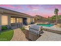 An outdoor kitchen and grill next to the refreshing pool with its rock waterfall feature at 11958 W Villa Chula Ln, Sun City, AZ 85373
